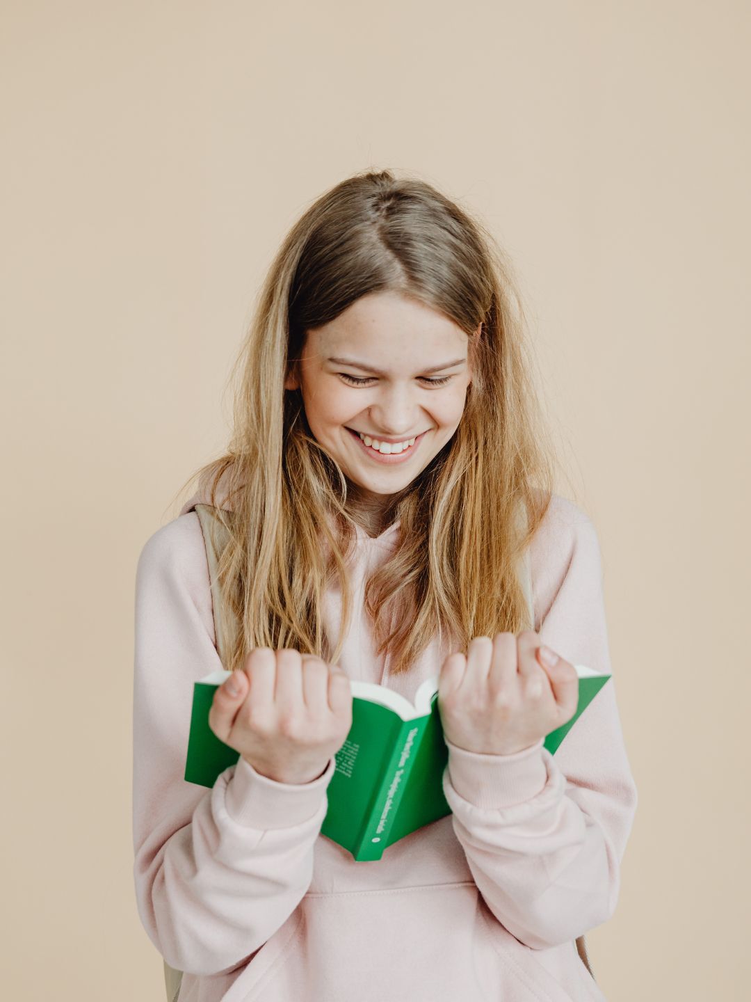 jeune fille souriante lisant un livre scolaire